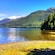 A bay surrounded by a forest and snowcapped mountains